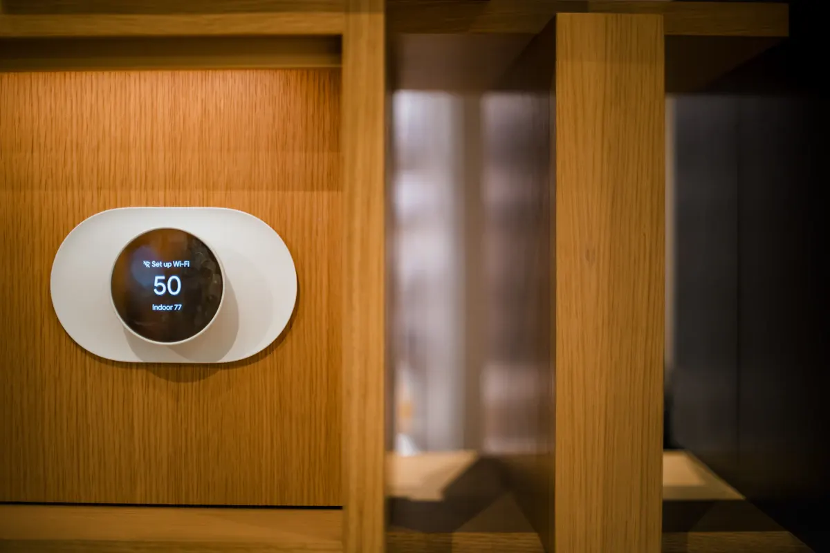 Round digital thermostat mounted on a timber wall