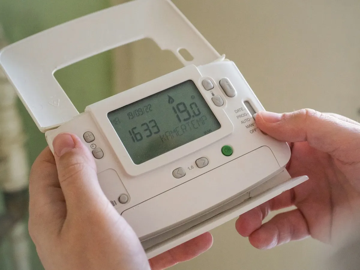 Hands adjusting a programmable heating controller